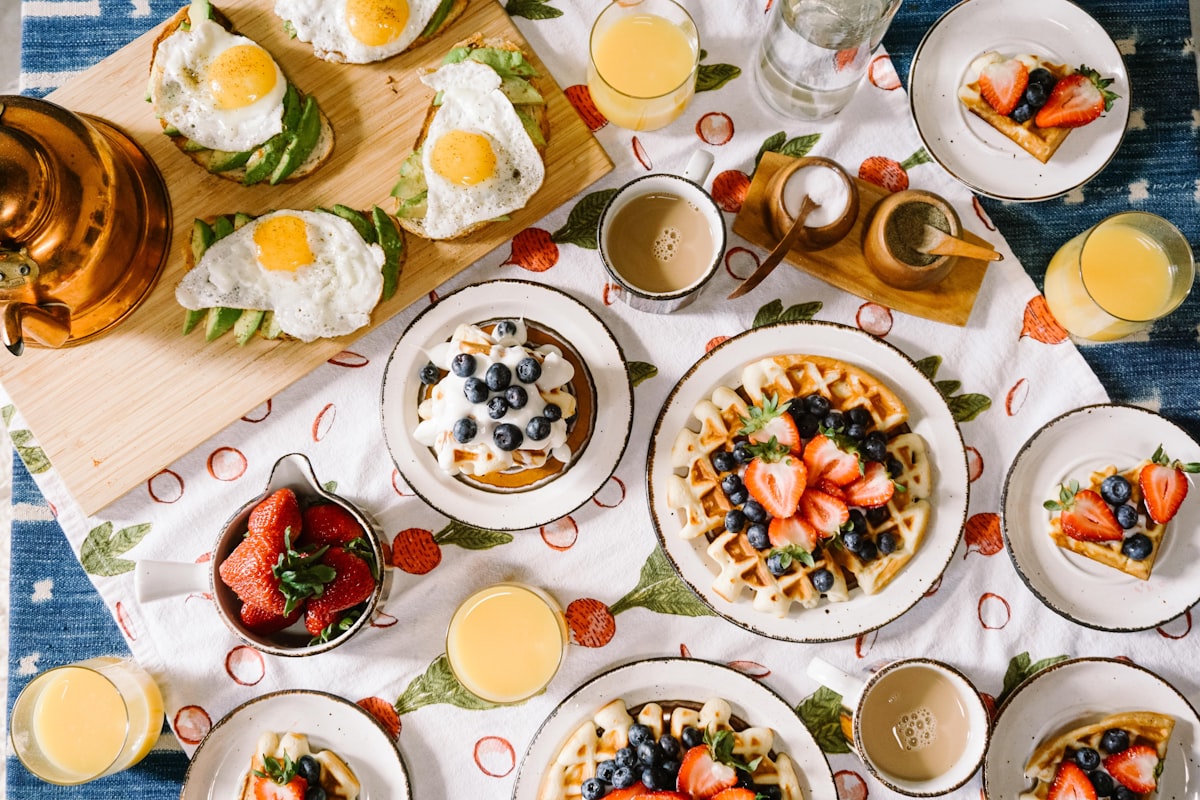Waffles with fruit and juice on a busy breakfast table