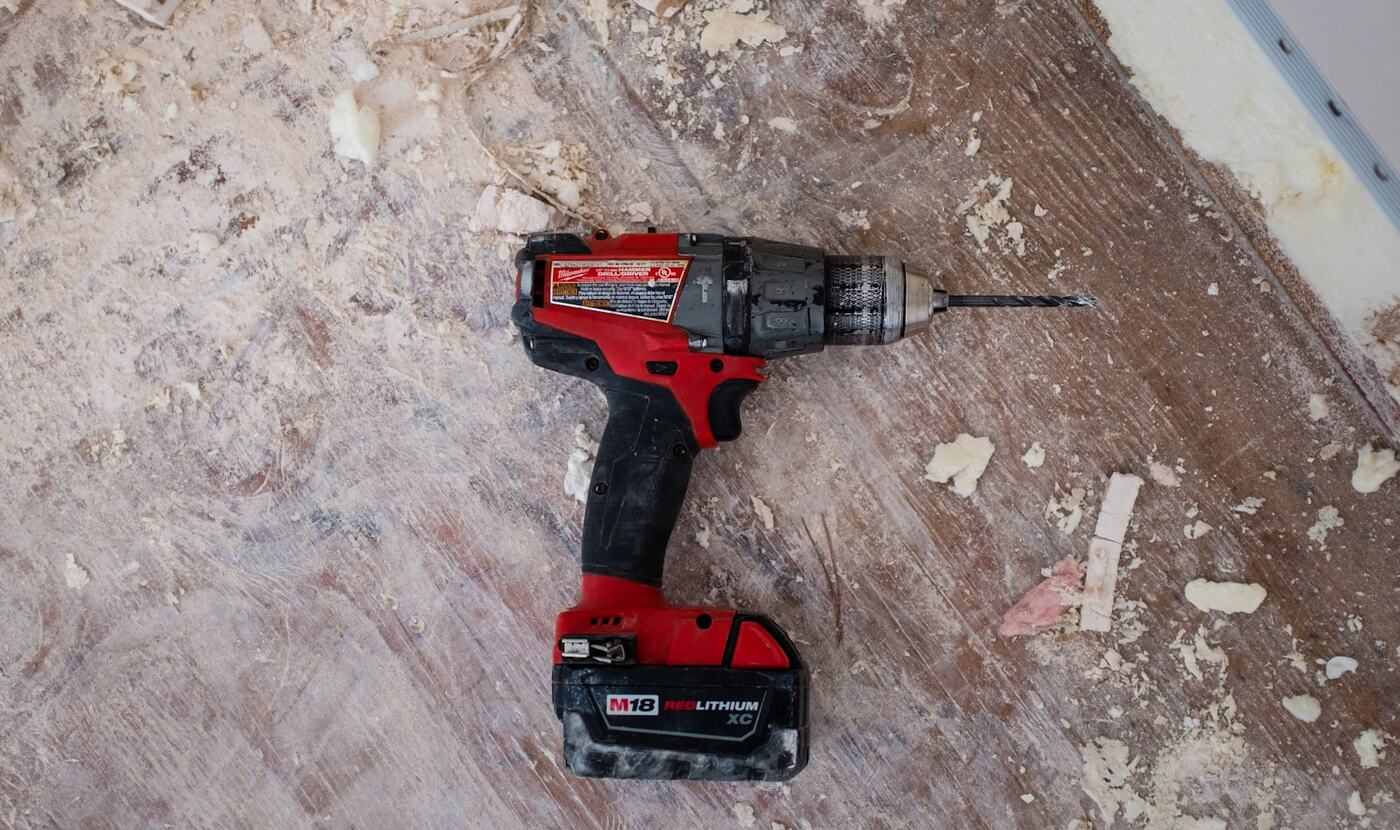 A drill resting on a dust covered floor mid renovation