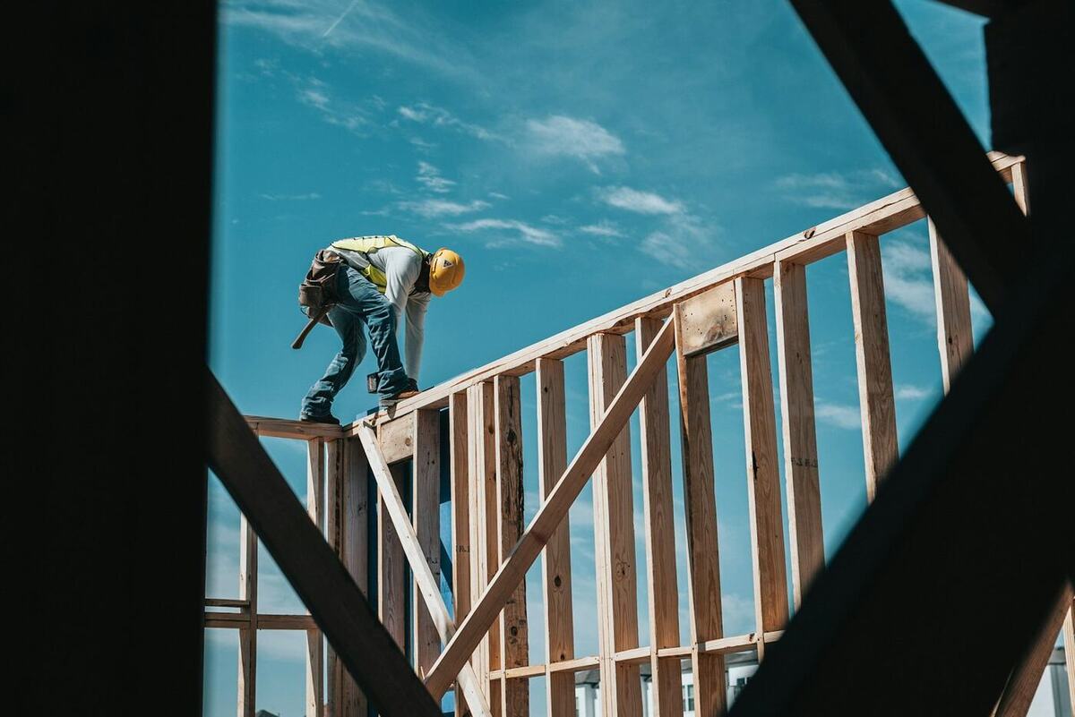 Carpenter fixing the timber roof structure of a loft conversion against a blue sky
