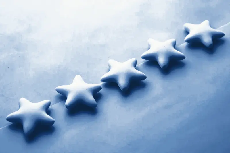 Five toy stars climbing a diagonal line across a plain surface, printed in Prussian blue.